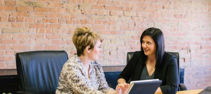 Image of two women at a conference table talking to each other. Photo by Amy Hirschi on Unsplash