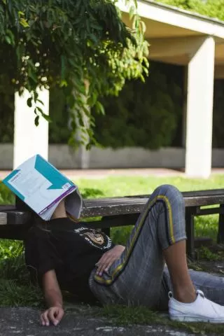 Photo by Tony Tran on Unsplash; image of a person lying with a book over their face